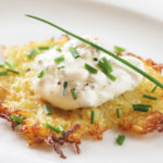Rösti Hüttenzauber, mit frischem Schnittlauch auf einem weißen Teller serviert.