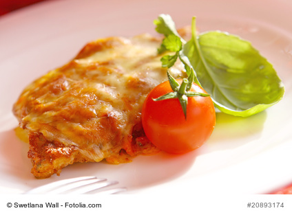 Calzone Schnitzel aus hauchdünnen Schweineschnitzel gemacht und mit einer frischen Tomate und Basilikum auf einem Teller serviert.