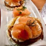 Blinis mit Lachs auf einer weißen Schale serviert.