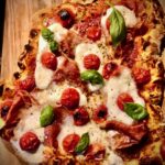 Pizza mit Mozzarella und Parmaschinken belegt.