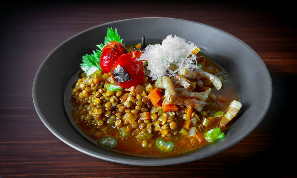 Linseneintopf in einer dunklen Schale serviert.