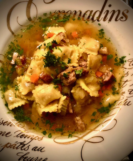 Rindersuppe mit Ravioli in einem tiefen Teller serviert.
