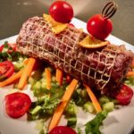 Rollbraten mit mediterranen Zutaten auf einem hellen Teller serviert.