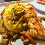 Knuspriger Zander mit Mandeln paniert und herrlich duftenden Kartoffelstampf der mit etwas Trüffel verfeinert wurde auf einem Teller mit Bohnengemüse.