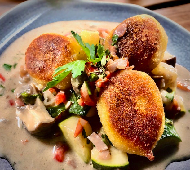 Gnocchi mit Pilzragout auf einem grauen Teller serviert.