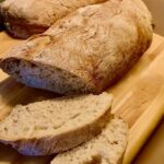 Selbstgemachtes Chiabatta-Brot mit Dinkelmehl auf einem Holzbrett angerichtet.