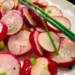 Radieschen-Salat mit frischem Schnittlauch auf einem dekorativen Teller serviert.
