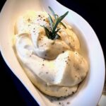 Selbstgemachte Mayonnaise mit einem frischen Rosmarin-Zweig in einer dekorativen Schale serviert.