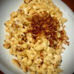 Allgäuer Käsespätzle mit Röstzwiebeln auf einem weißen Teller angerichtet.