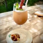 Ein naturtrüber Traubenspritz in einem Glass mit ein paar roten Weintrauben am Spieß angerichtet.