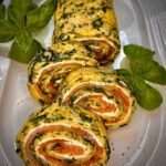 Lachsrolle Low Carb auf einer Platte mit etwas Basilikum angerichtet.