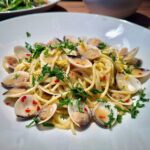 Spaghetti vongole auf einem weißen Teller mit Petersilie angerichtet und garniert.