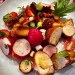 Breznsalat mit Petersilie auf einem weißen Teller angerichtet.