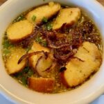 Aufgeschmolzene bayerische Breznsuppe in einem Suppenteller angerichtet und mit Schnittlauch garniert.