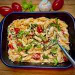 Pasta aus dem Ofen mit Feta, Spinat und Cocktailtomaten in der Auflaufform serviert.