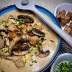 Brotsuppe mit Champignons in einer dekorativen Schüssel zum Servieren.