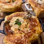 Eine mit Blätterteig überbackene Gulaschsuppe frisch aus dem Ofen kommend.