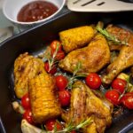 Rosmarin-Hähnchen mit Cocktailtomaten und Maiskolben in der Auflaufform aus dem Ofen.