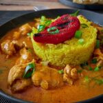 Butter Chicken Curry mit Kurkuma-Reis serviert.
