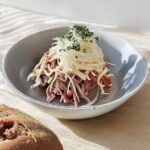Schweizer Wurstsalat in einer Servierschüssel angerichtet.