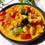 Wok-Gemüse mit Garnelen im einer Schale serviert.