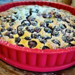 Frischer duftender Blaubeerkuchen aus dem Ofen mit Puderzucker bestreut in einer Backform.