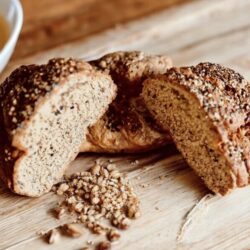 Roggen-Dingel-Brot, frisch gebacken und auf einer einer Holzunterlage angerichtet.