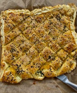 Blätterteig Zupfbrot mit gerösteten Auberginen, Kräuterfrischkäse und Cheddar als Füllung. Teig in Rauten geschnitten und mit weißem und dunklem Sesam gebacken. Auf einem Backpapier rustikal serviert.