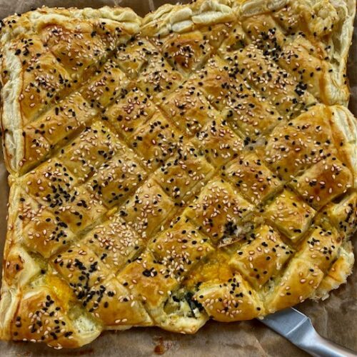 Blätterteig Zupfbrot mit gerösteten Auberginen, Kräuterfrischkäse und Cheddar als Füllung. Teig in Rauten geschnitten und mit weißem und dunklem Sesam gebacken. Auf einem Backpapier rustikal serviert.