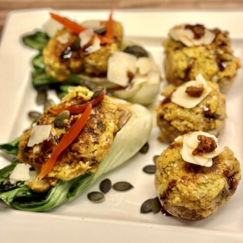 Drei pralle, goldbraune Champignons, gefüllt mit einer würzigen Falafel-Mischung, ruhen auf einem Bett aus knackig gegrilltem Pak Choi. Bestreut mit leuchtend grünen Kürbiskernen und feinem Parmesan, vollendet durch die dunkle Spur einer Balsamico-Creme. Ein Fest für die Sinne.