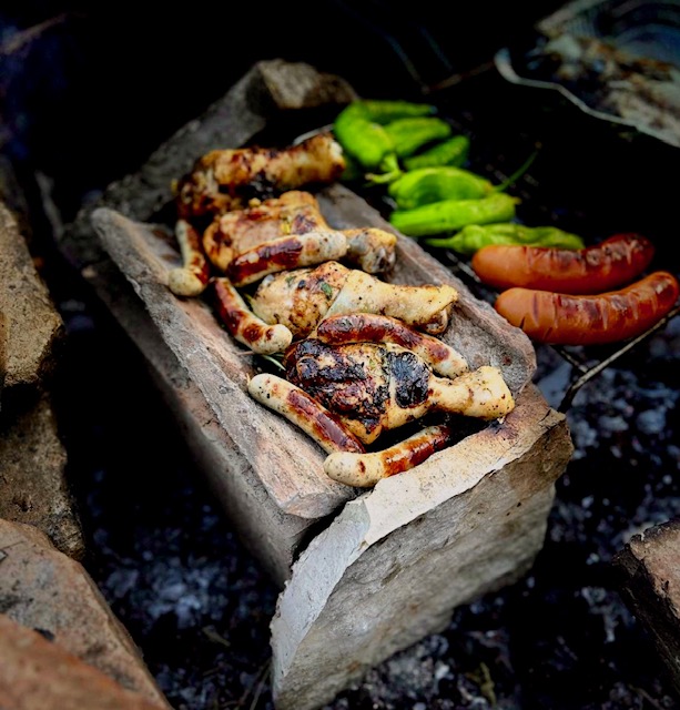 Eine alte Dachziegel auf dem Grill als Grill-Hack mit saftigen Hähnchen und Würstchen kurz vor dem servieren.