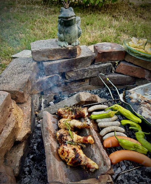 En Grill mit Rost und Dachziegeln und Grillgut darauf. 