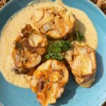 Geröstete Weißwurst-Knödel mit einer leckeren Senfsoße auf einem blauen Teller serviert.