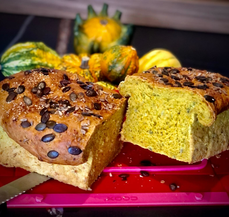 Kürbisbrot in der Coox-Wunderform gebacken und im Hintergrund mit Kürbissen dekoriert.