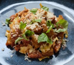 Salsiccia-SpitzkohlPfanne (neu) auf einem dunklen Teller angerichtet und mit Parmesan und Basilikum dekoriert.