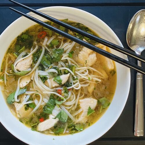 Pho Ga Suppe mit Huhn & Reisnudeln in einer Schale serviert. Wer mag kann die Reisnudeln gerne mit Stäbchen essen, so richtig traditionell.