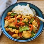 Rotes Thai-Curry mit Hähnchenbrustfilet in einer Schale mit Basmatireis serviert.