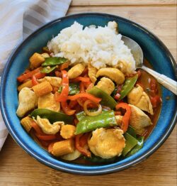 Rotes Thai-Curry mit Hähnchenbrustfilet in einer Schale mit Basmatireis serviert.