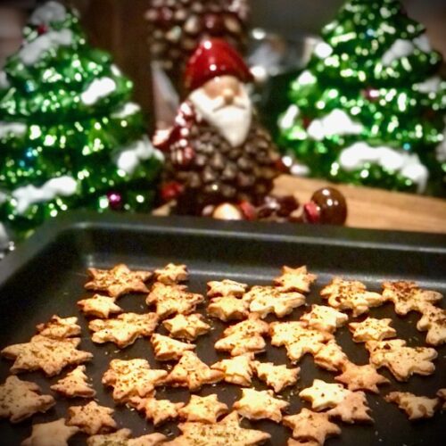 Herzhafte Parmesan Plätzchen in Stern- und Tannenbaumform auf dem Harecker Backblech vor weihnachtlicher Dekoration.