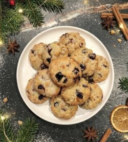 Wenige, festliche Mini-Stollen angerichtet auf einem großen Teller auf einer dunklen Stein-Küchenarbeitsplatte mit weihnachtlicher Dekoration – Inspiration für die Weihnachtsbäckerei mit Pfannen Harecker.