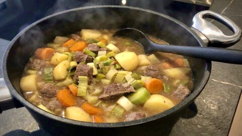 Frisch gekochter, dampfender Pichelsteiner Eintopf in einem Pfannen Harecker Kochtopf auf dem Herd, servierbereit mit einem Silikon Kochlöffel.