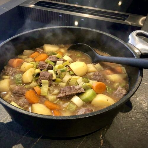 Frisch gekochter, dampfender Pichelsteiner Eintopf in einem Pfannen Harecker Kochtopf auf dem Herd, servierbereit mit einem Silikon Kochlöffel.