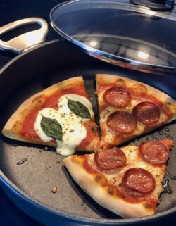 Eine frisch wie frisch gebackene und aufgewärmte Pizza in einer Harecker Pfanne mit Decker auf einem Cerankochfeld.