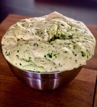 Bärlauch-Fougasse Teig aufgegangen in einer silberenen Küchenschüssel auf einem rustikalen Brett in der Küche.