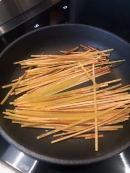 Rohe Spaghetti in einer schwarzen Pfanne von Pfanne Harecker etwas angeröstet it Olivenöl