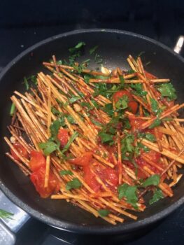 In diesem Schritt werden den angebratenen Nudeln noch etwas Petersilie und Tomaten zum "einkochen" beigefügt und es wird in der Pfanne weiter gebraten bis alles etwas dunkel geworden ist.