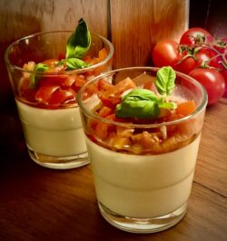 Servierfertige herzhafte Parmesan Panna Cotta mit fruchtigem Tomaten-Topping und frischen Kräutern als appetitanregender Gruß aus der Küche.