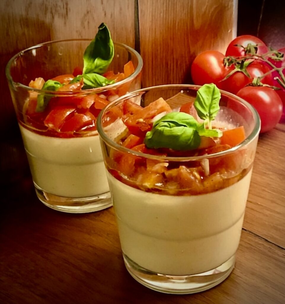 Servierfertige herzhafte Parmesan Panna Cotta mit fruchtigem Tomaten-Topping und frischen Kräutern als appetitanregender Gruß aus der Küche.